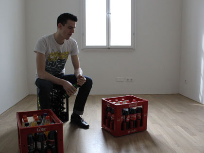 WG-Bewohner sitzt auf Getränkekiste in leerem Zimmer
